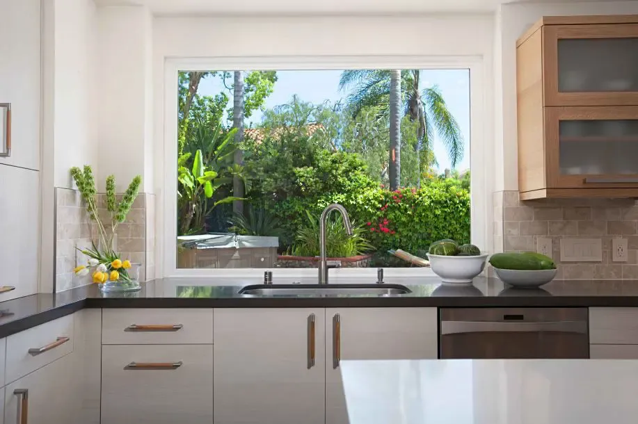 Cocina reformada con una gran ventana de PVC sobre el fregadero abierta al jardín en Girona