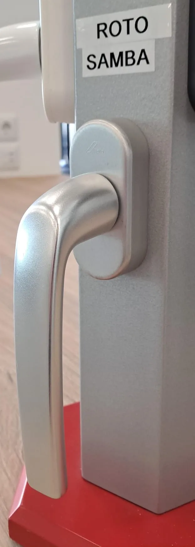 Detall d'una maneta rodona de color plata muntada sobre un perfil de finestra
