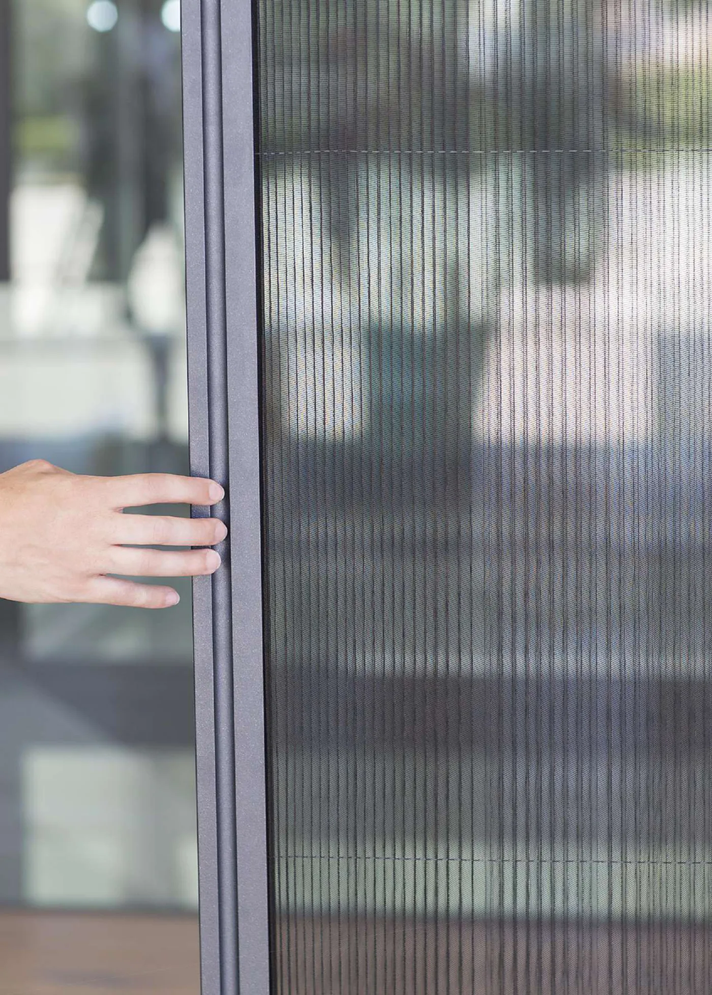 Mosquitera plisada con tejido plegado instalada en una puerta, accionada con la mano