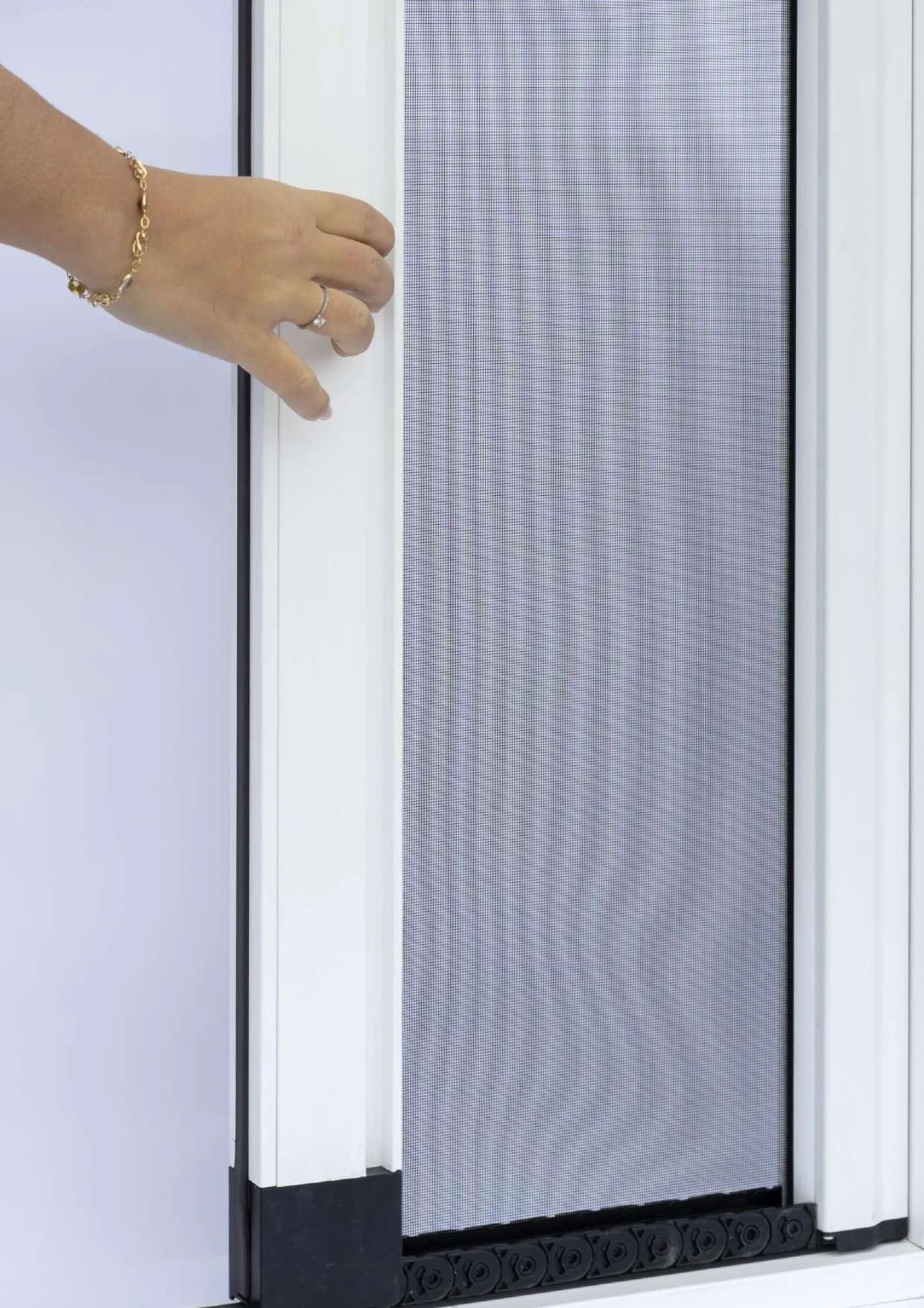 Mosquitera de marco de aluminio blanco instalada en una ventana, manipulada con la mano
