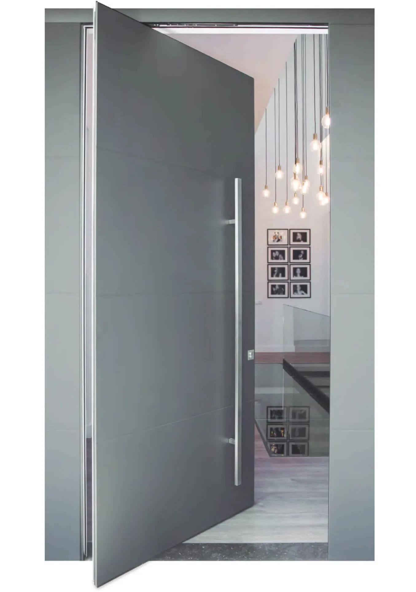 Puerta de entrada de aluminio pivotante de hoja oculta en gris instalada en un interior moderno con escalera