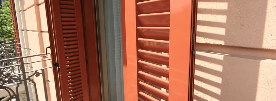 Porticó de lames fixes d'alumini en color teula sobre una façana