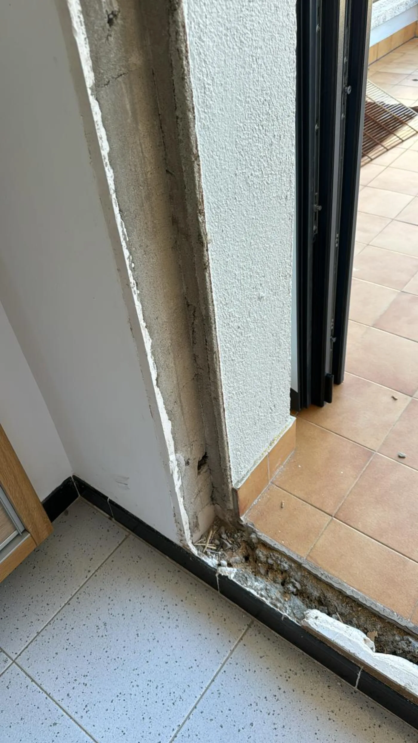 Brancal i llindar de l'obertura amb la fusta vella picada i la paret a la vista, llest per rebre el nou marc