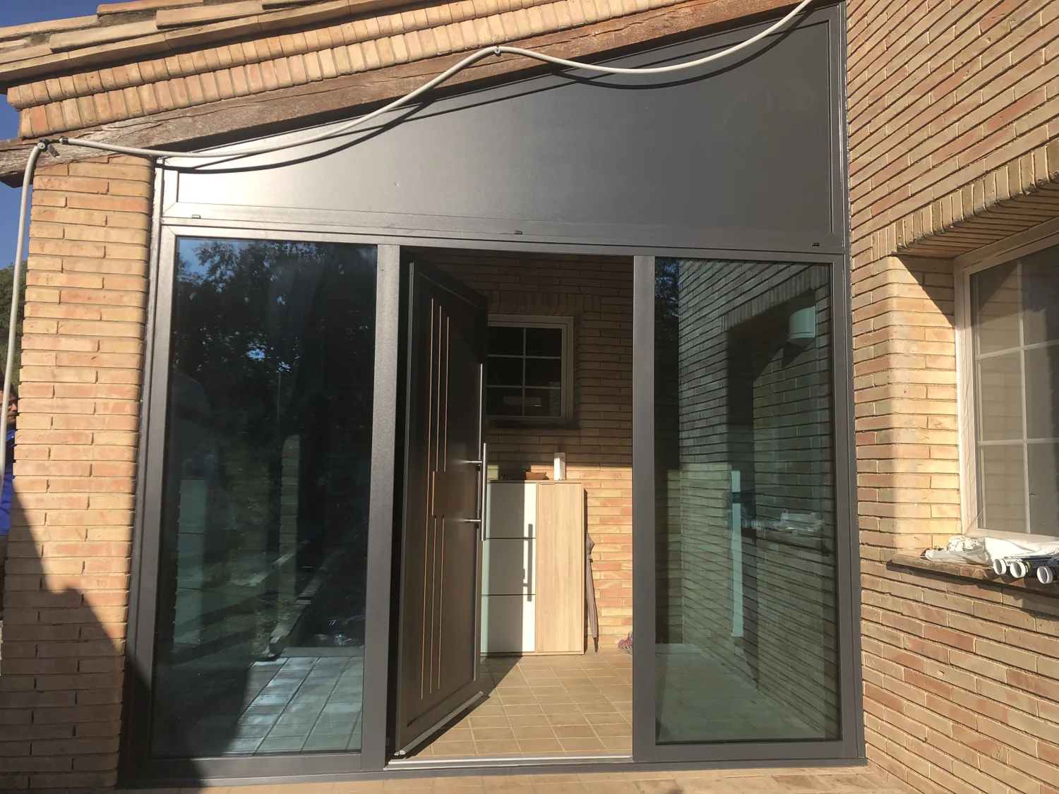 Porche acristalado con puerta de entrada de diseño en Porqueres