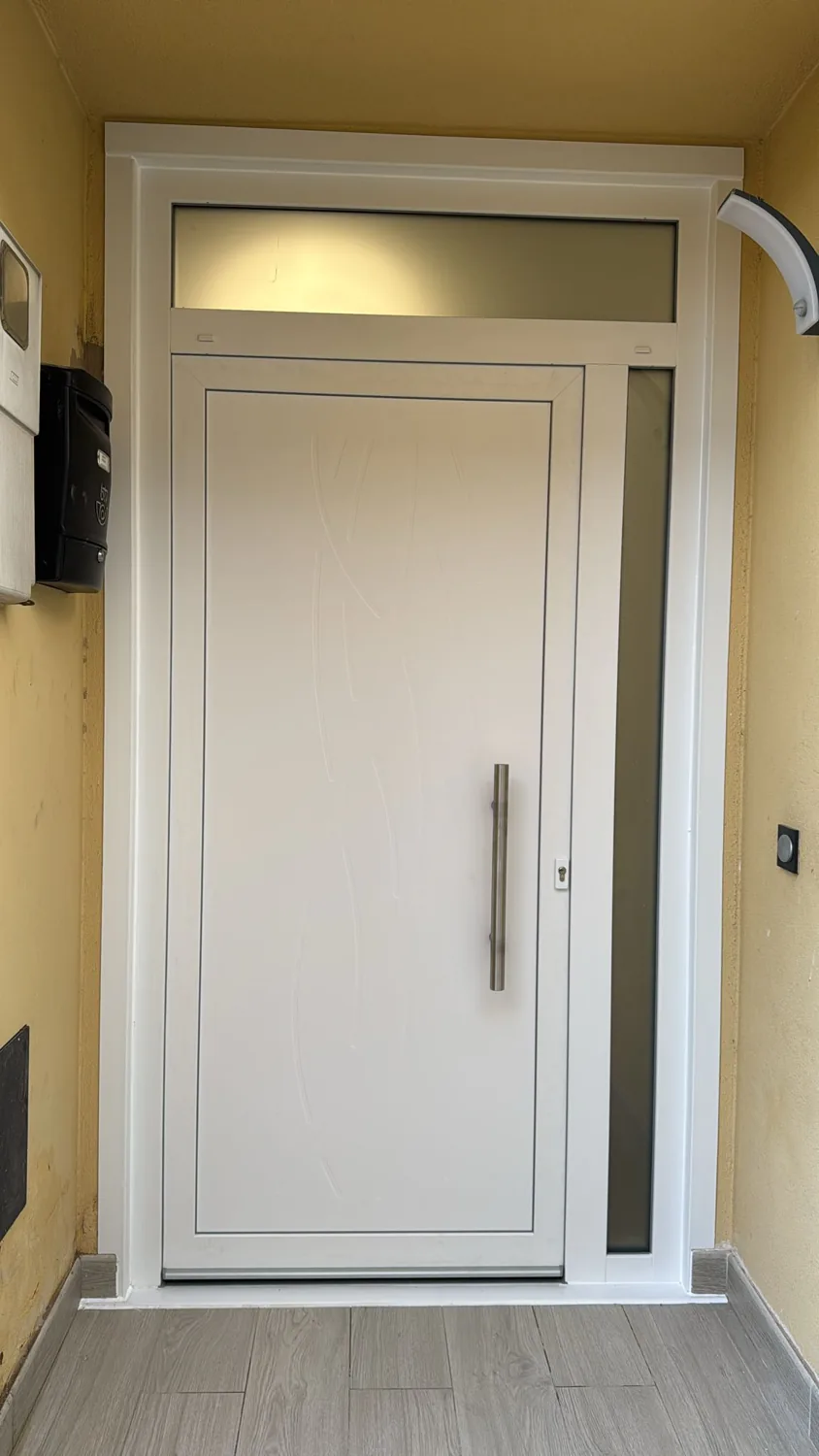 Puerta de entrada blanca con panel decorativo en Vilobí d'Onyar