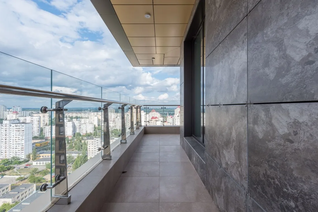 Terraza de ático con barandilla de cristal y vistas panorámicas a la ciudad